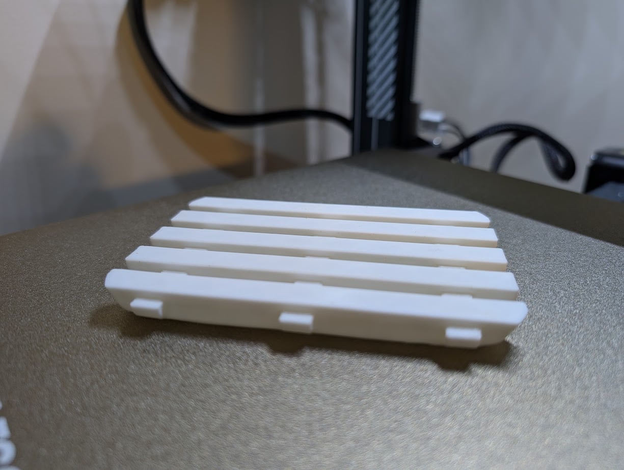 White slatted 3D printed soap tray on a printer bed